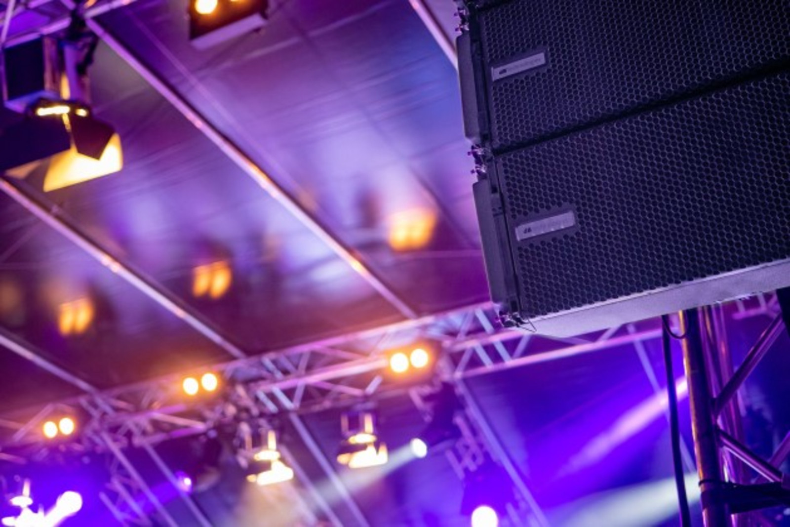 Bühnentraversen mit Line-Array-Lautsprechern und violettem Eventlicht.